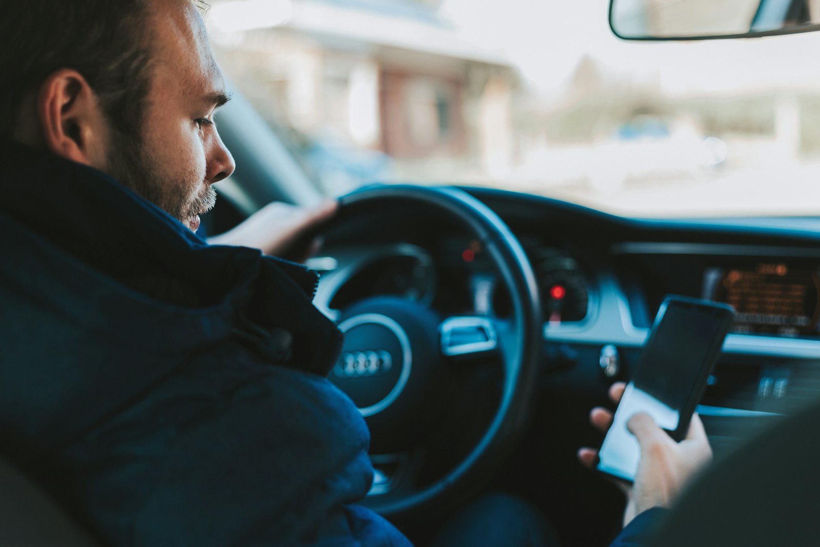 Driver holding smartphone near steering wheel